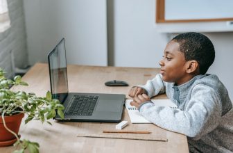 Jeune enfant faisant ses devoir avec un ordinateur